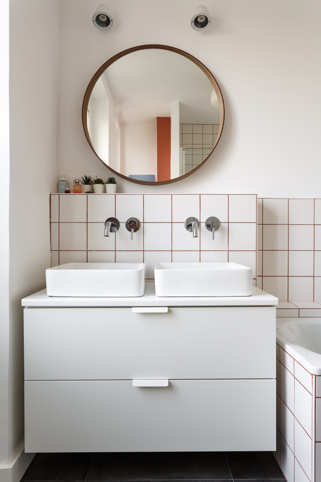 Идея дизайна: маленькая ванная комната в скандинавском стиле с плоскими фасадами, серыми фасадами, накладной ванной, белой плиткой, белыми стенами, настольной раковиной, черным полом, белой столешницей и зеркалом с подсветкой для на участке и в саду