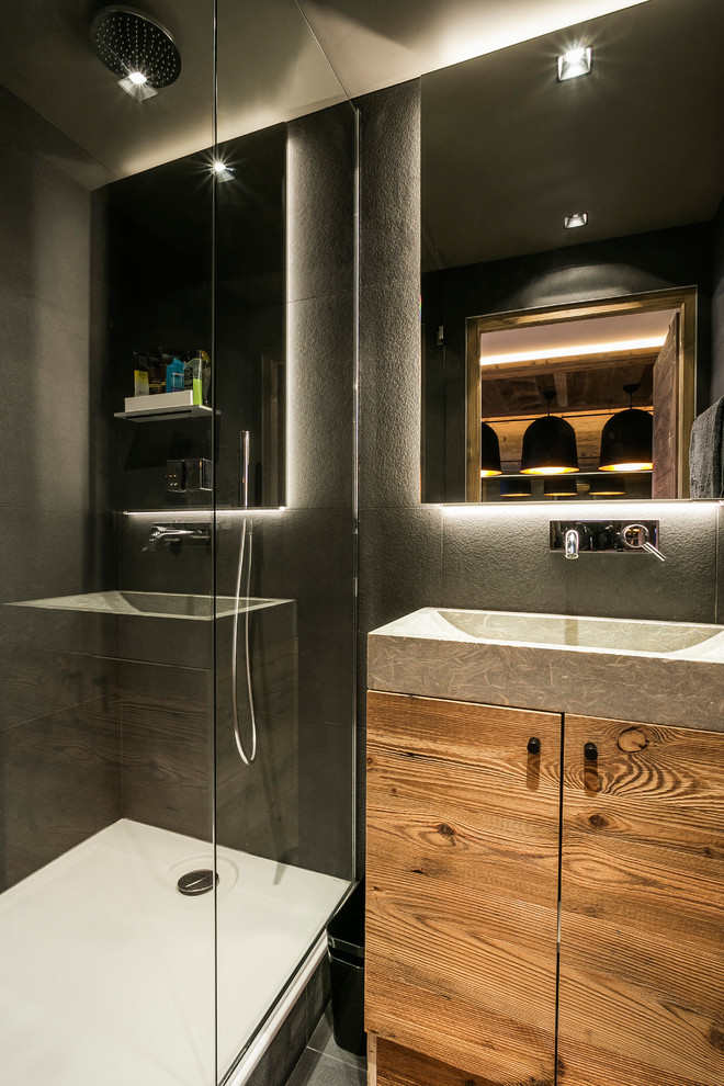 Inspiration pour une salle de bain design en bois brun avec un carrelage noir, un mur noir et une vasque.