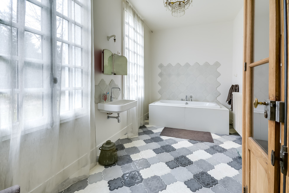 Immagine di una stanza da bagno padronale mediterranea di medie dimensioni con vasca freestanding, piastrelle bianche, pareti bianche e lavabo sospeso