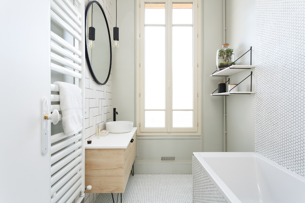 На фото: главная ванная комната среднего размера в скандинавском стиле с плоскими фасадами, светлыми деревянными фасадами, накладной ванной, душем над ванной, раздельным унитазом, белой плиткой, керамогранитной плиткой, белыми стенами, полом из мозаичной плитки, настольной раковиной, столешницей из искусственного камня, белым полом, душем с распашными дверями и белой столешницей