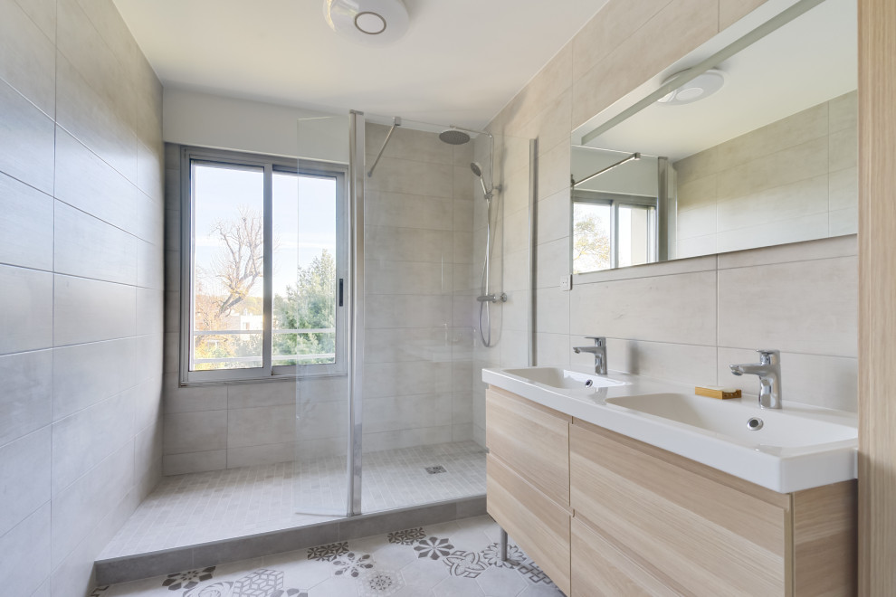 Mittelgroßes Modernes Duschbad mit hellen Holzschränken, Duschnische, beigen Fliesen, integriertem Waschbecken, buntem Boden, Falttür-Duschabtrennung, weißer Waschtischplatte und flächenbündigen Schrankfronten