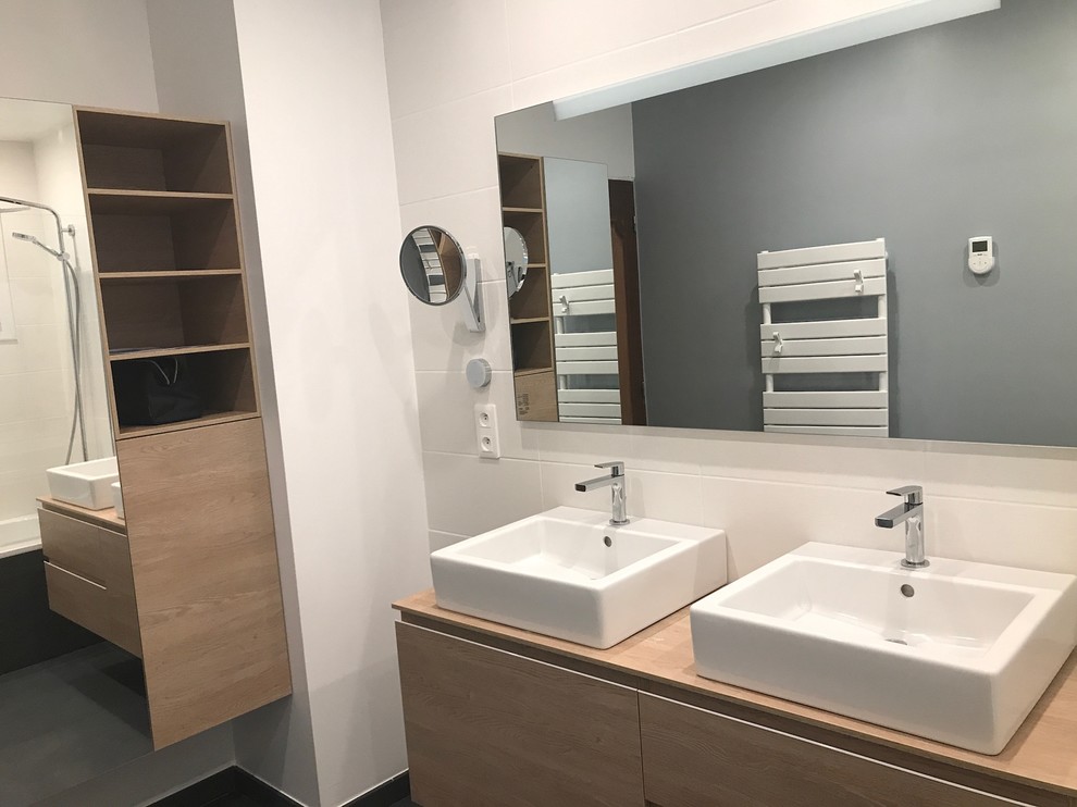 Cette photo montre une salle de bain tendance avec des portes de placard blanches, une baignoire en alcôve, un carrelage blanc, des carreaux de céramique, un mur blanc, un sol en carrelage de céramique, un lavabo intégré, un sol noir et un plan de toilette marron.
