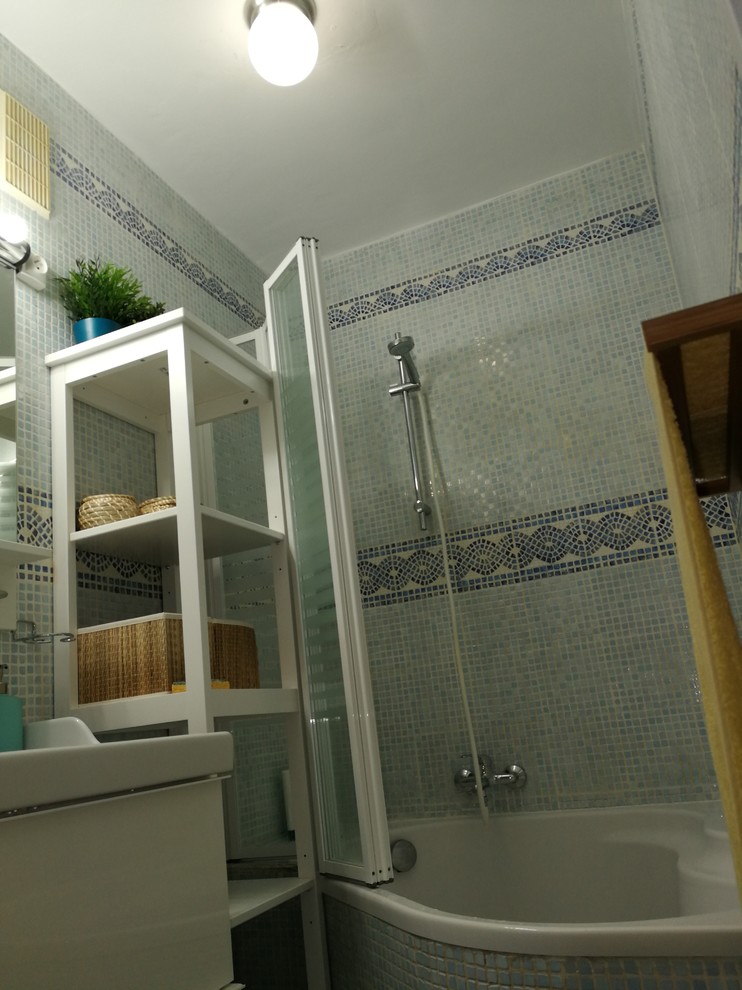 Réalisation d'une petite salle de bain principale marine avec une baignoire d'angle, un sol en carrelage de céramique, un sol bleu, mosaïque, un mur bleu, une vasque et une cabine de douche à porte battante.