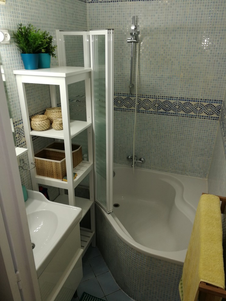Exemple d'une petite salle de bain principale bord de mer avec une baignoire d'angle, mosaïque, un sol en carrelage de céramique, un sol bleu, un mur bleu, une vasque et une cabine de douche à porte battante.