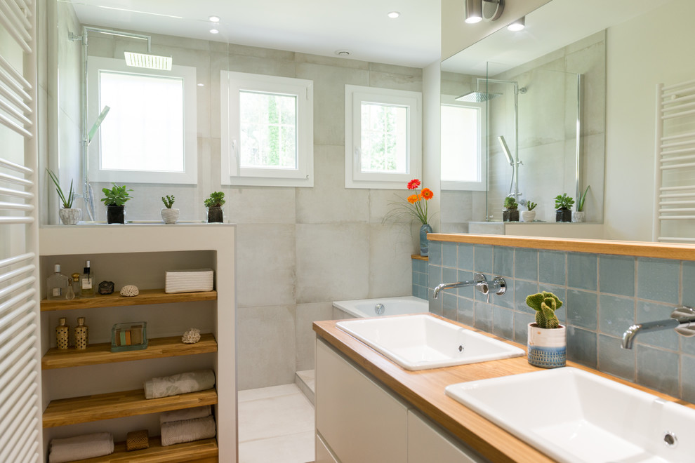 Cette image montre une salle de bain principale traditionnelle de taille moyenne avec une baignoire encastrée, une douche à l'italienne, un carrelage gris, des carreaux de céramique, un mur gris, parquet clair, un plan vasque, un plan de toilette en bois et aucune cabine.