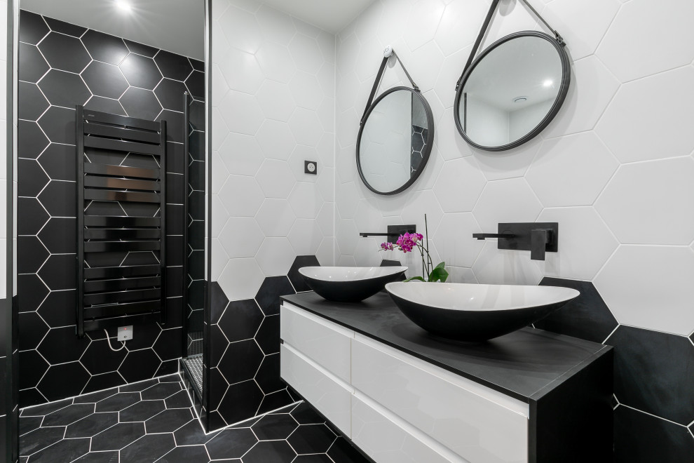 Cette image montre une salle de bain design de taille moyenne avec un placard à porte plane, des portes de placard blanches, un carrelage noir et blanc, des carreaux de porcelaine, un sol en carrelage de porcelaine, une vasque, un sol noir, un plan de toilette noir et meuble-lavabo suspendu.