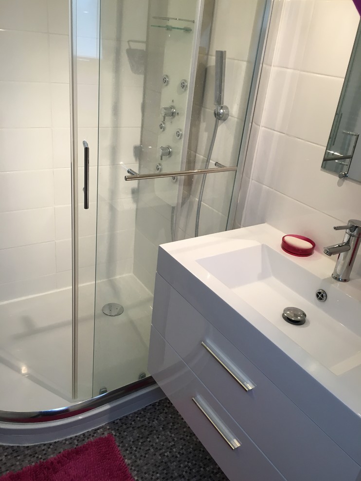 Cette image montre une salle de bain principale design de taille moyenne avec un placard à porte affleurante, des portes de placard blanches, une douche d'angle, un carrelage rose, des carreaux de céramique, un mur blanc, un sol en linoléum, un lavabo suspendu et un plan de toilette en surface solide.