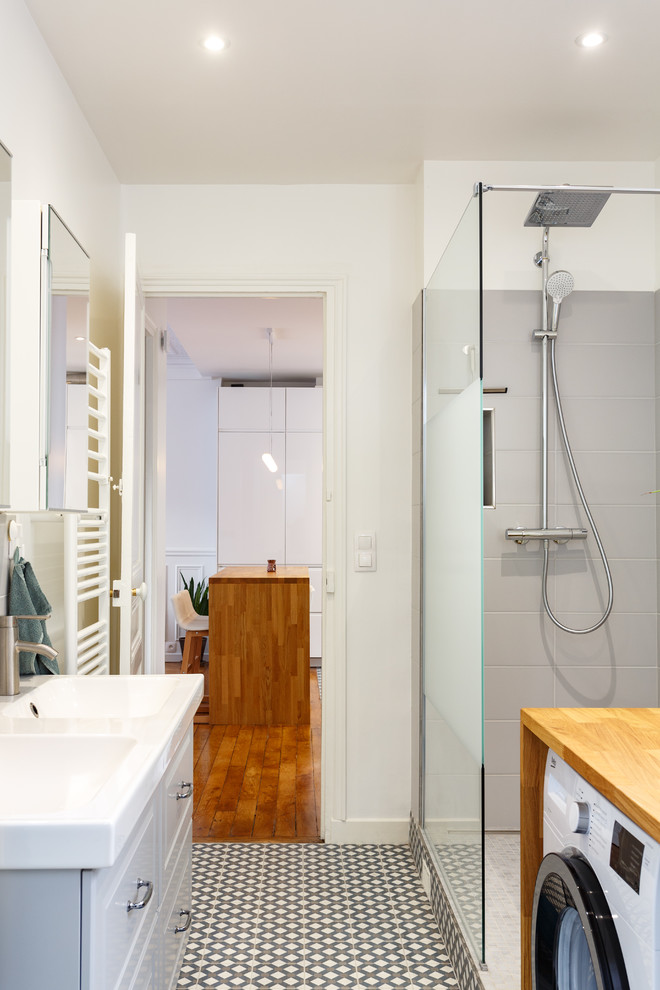 Walk-in shower - mid-sized modern master gray tile and ceramic tile cement tile floor and multicolored floor walk-in shower idea in London with raised-panel cabinets, white cabinets, a two-piece toilet, white walls, a console sink, solid surface countertops and white countertops