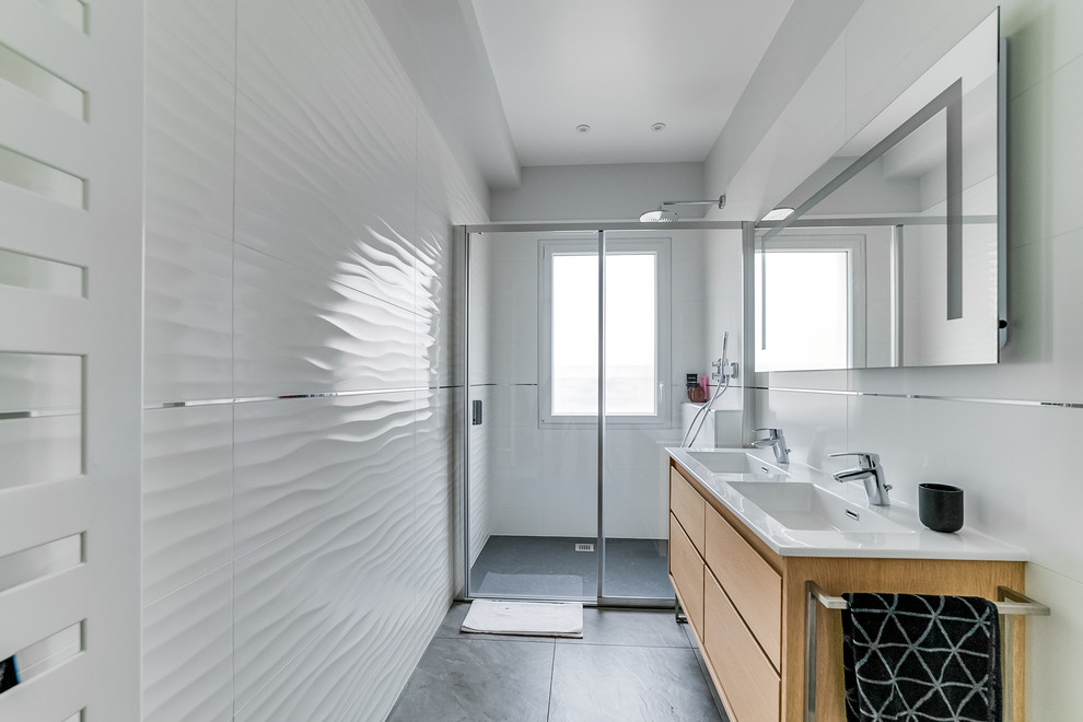 Источник вдохновения для домашнего уюта: главная ванная комната среднего размера в современном стиле с фасадами с филенкой типа жалюзи, светлыми деревянными фасадами, душем без бортиков, белой плиткой, белыми стенами, монолитной раковиной, серым полом и душем с раздвижными дверями