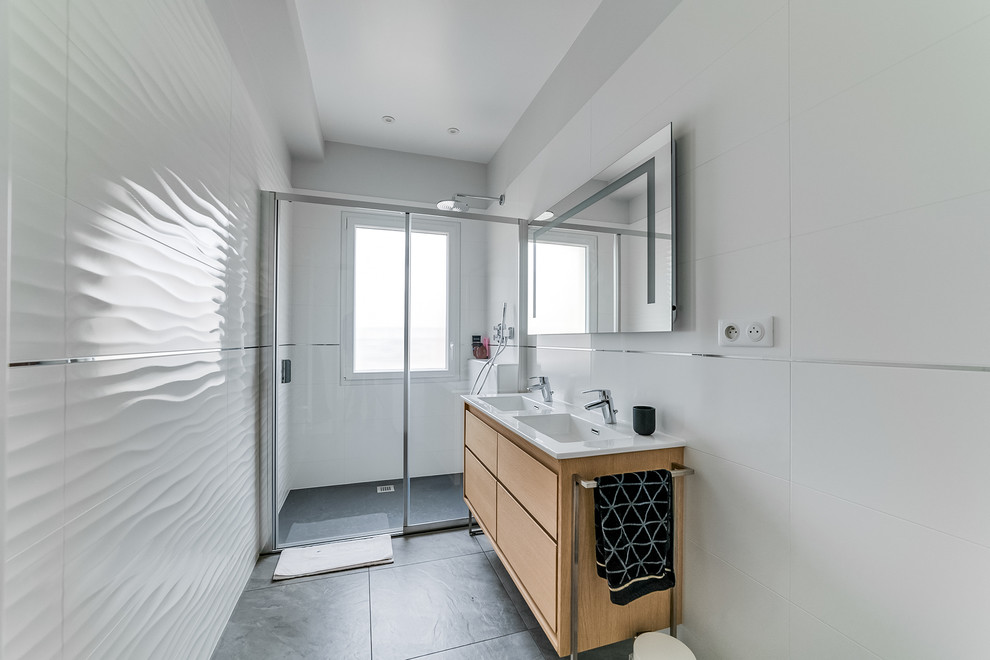 Aménagement d'une salle de bain principale contemporaine en bois clair de taille moyenne avec un placard à porte persienne, une douche à l'italienne, un carrelage blanc, un mur blanc, un lavabo intégré, un sol gris et une cabine de douche à porte coulissante.