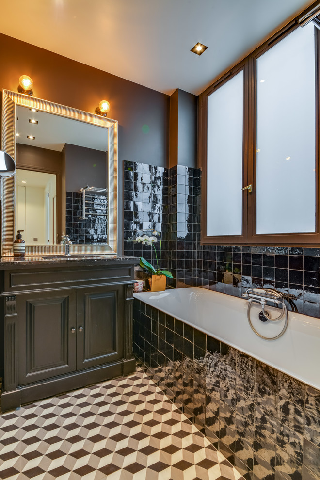Идея дизайна: главная ванная комната среднего размера в современном стиле с фасадами с филенкой типа жалюзи, серыми фасадами, полновстраиваемой ванной, черной плиткой, коричневыми стенами, полом из цементной плитки, врезной раковиной и разноцветным полом
