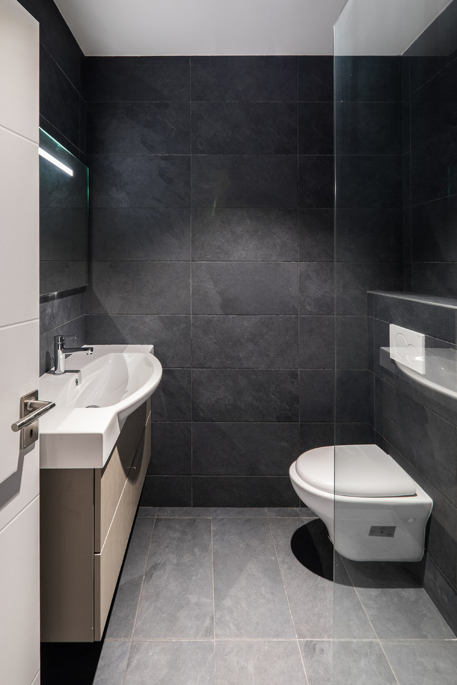 Foto di una piccola stanza da bagno con doccia minimal con ante nere, doccia a filo pavimento, WC sospeso, piastrelle nere, pareti nere, lavabo rettangolare, pavimento nero e doccia aperta