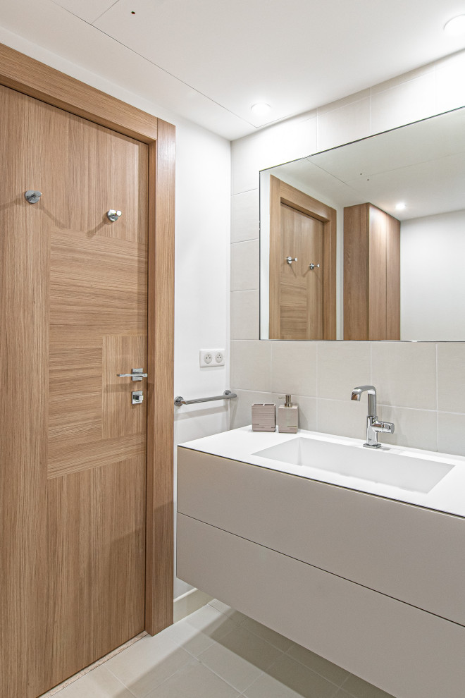 Photo of a medium sized contemporary bathroom in Nice with recessed-panel cabinets, beige cabinets, a submerged bath, a wall mounted toilet, grey tiles, cement tiles, white walls, cement flooring, a console sink, stainless steel worktops, beige floors, an open shower and white worktops.