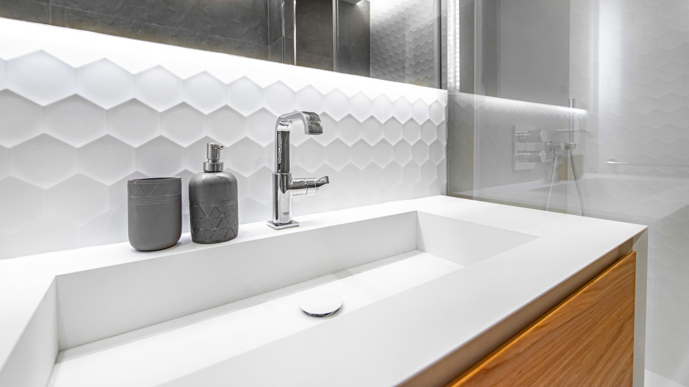 Modern inredning av ett mellanstort en-suite badrum, med en kantlös dusch, en vägghängd toalettstol, vit kakel, keramikplattor, vita väggar, klinkergolv i keramik, ett konsol handfat, grått golv och dusch med skjutdörr