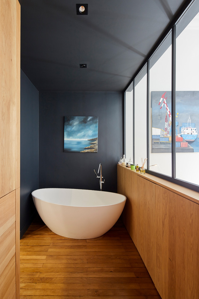 Inspiration for a medium sized contemporary bathroom in Nantes with a freestanding bath, black walls, brown floors and medium hardwood flooring.