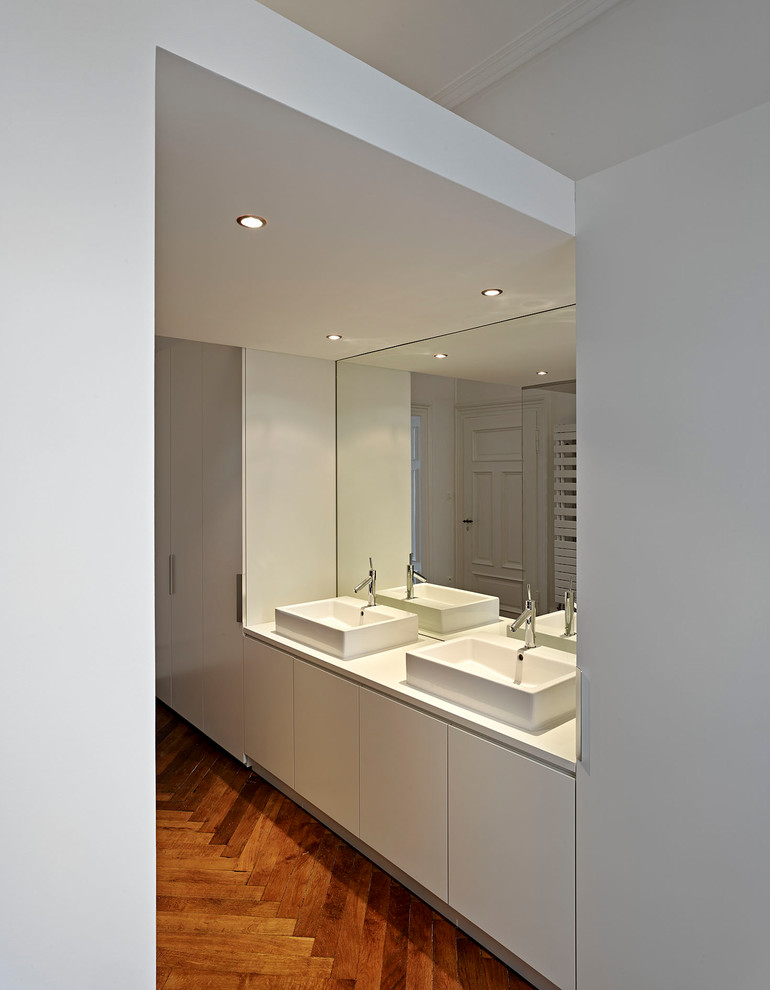 Modelo de cuarto de baño minimalista de tamaño medio con puertas de armario blancas, ducha abierta, baldosas y/o azulejos grises, paredes grises, suelo de madera oscura, suelo marrón y ducha abierta