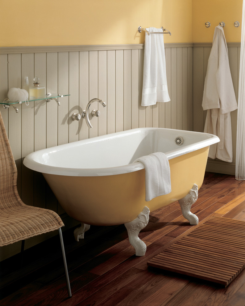 Réalisation d'une salle de bain grise et jaune victorienne avec une baignoire sur pieds, un combiné douche/baignoire, un mur multicolore, un sol en bois brun et un sol marron.