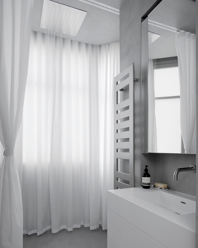 Aménagement d'une salle de bain principale contemporaine avec un placard à porte affleurante, des portes de placard blanches, un carrelage gris, du carrelage en marbre, un mur gris, sol en béton ciré et un sol gris.