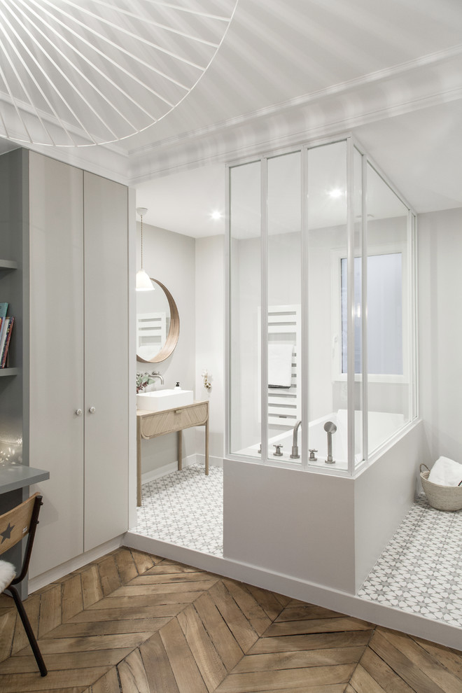 Design ideas for a medium sized scandinavian family bathroom in Paris with beaded cabinets, grey cabinets, a submerged bath, grey walls, cement flooring, a built-in sink, wooden worktops, grey floors, a shower/bath combination, a wall mounted toilet, grey tiles, ceramic tiles, a hinged door, beige worktops, a single sink and a freestanding vanity unit.