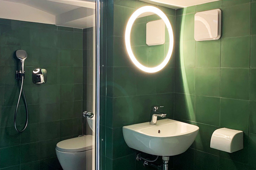 Idéer för att renovera ett litet funkis vit vitt badrum med dusch, med en kantlös dusch, en vägghängd toalettstol, grön kakel, cementkakel, gröna väggar, klinkergolv i keramik, ett väggmonterat handfat, beiget golv och med dusch som är öppen