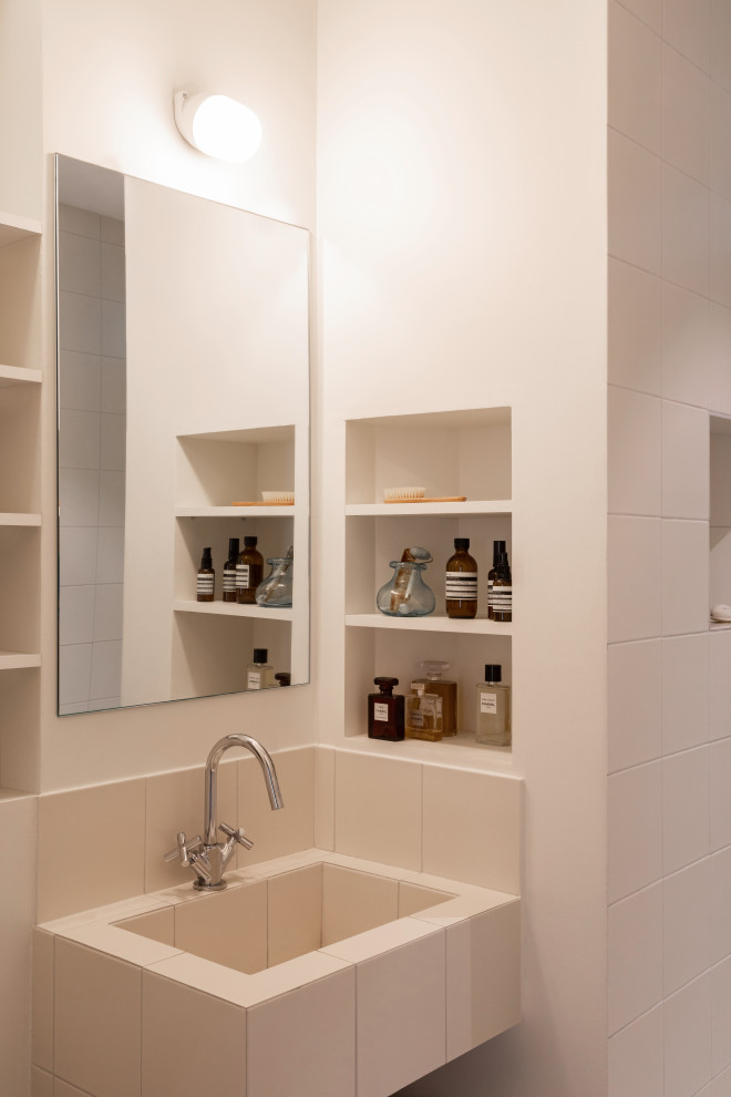 Idee per una piccola stanza da bagno con doccia minimal con doccia a filo pavimento, piastrelle beige, piastrelle in ceramica, pareti bianche, pavimento in cemento, top piastrellato, pavimento grigio, top beige, nicchia e un lavabo