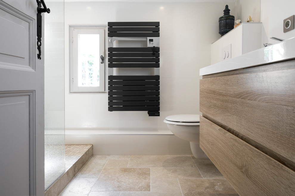 Idéer för små nordiska badrum med dusch, med en kantlös dusch, en vägghängd toalettstol, travertinkakel, vita väggar, travertin golv, ett konsol handfat och beiget golv