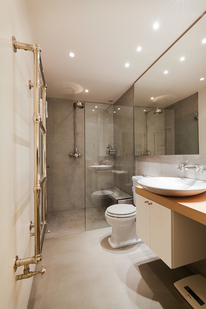 Idéer för att renovera ett mellanstort eklektiskt beige beige badrum med dusch, med en kantlös dusch, en toalettstol med hel cisternkåpa, grå kakel, grå väggar, betonggolv, ett nedsänkt handfat, träbänkskiva, grått golv, släta luckor, vita skåp och dusch med gångjärnsdörr