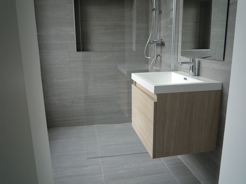 Modern inredning av ett badrum med dusch, med en kantlös dusch, grå kakel, keramikplattor, grå väggar och klinkergolv i keramik