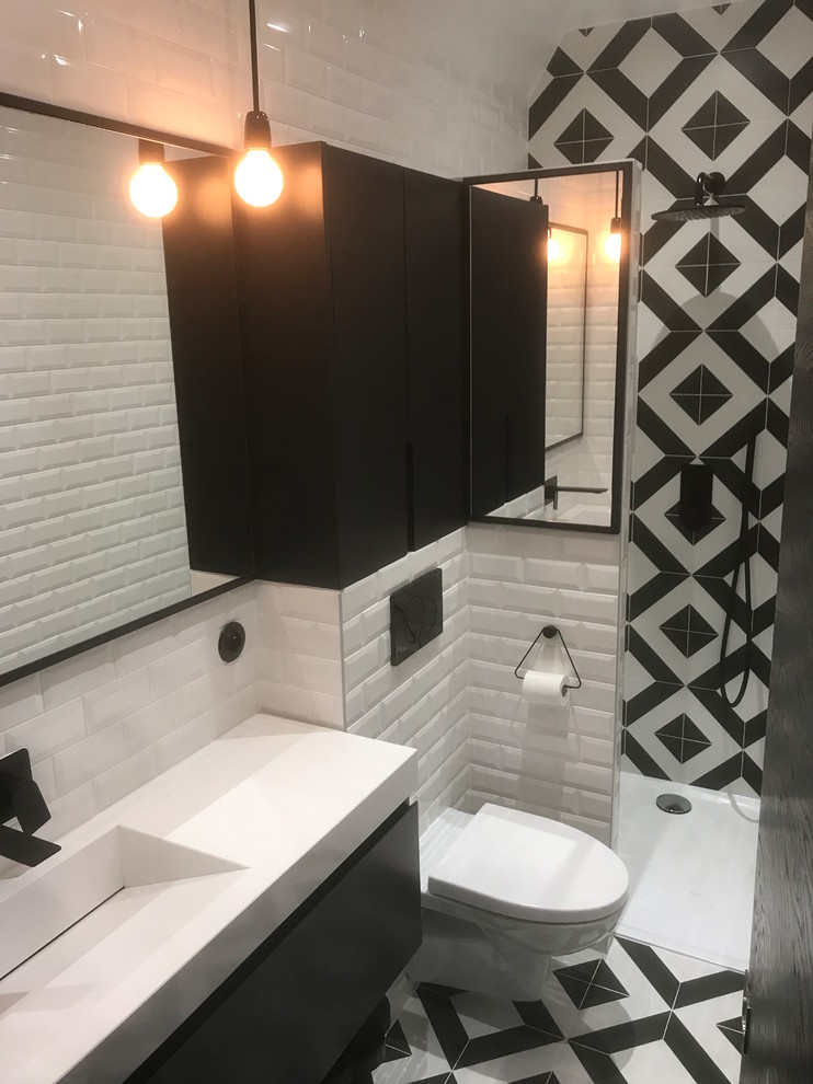 パリにある高級な小さなコンテンポラリースタイルのおしゃれなマスターバスルーム (黒いキャビネット、バリアフリー、壁掛け式トイレ、白いタイル、黒いタイル、サブウェイタイル、白い壁、セラミックタイルの床、一体型シンク、珪岩の洗面台、白い床、白い洗面カウンター) の写真