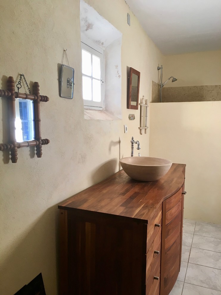 Стильный дизайн: маленькая ванная комната в стиле кантри с темными деревянными фасадами, душем без бортиков, бежевой плиткой, плиткой из травертина, бежевыми стенами, душевой кабиной, накладной раковиной и столешницей из дерева для на участке и в саду - последний тренд
