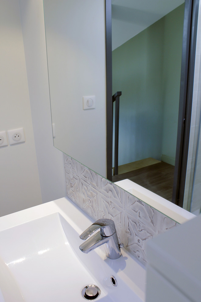 Esempio di una piccola stanza da bagno minimal con ante bianche, WC sospeso, piastrelle beige, piastrelle in ceramica, pareti beige, pavimento in laminato, lavabo integrato e porta doccia a battente