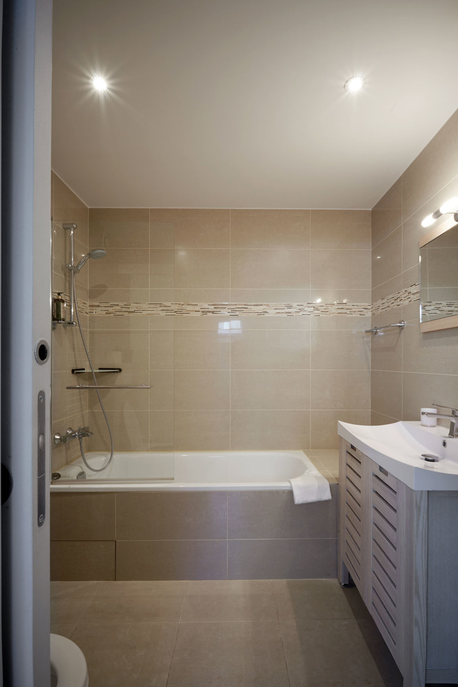На фото: главная ванная комната в современном стиле с фасадами с филенкой типа жалюзи, светлыми деревянными фасадами, инсталляцией, бежевой плиткой, бежевыми стенами и раковиной с несколькими смесителями