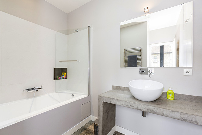 Inspiration för ett mellanstort funkis en-suite badrum, med bänkskiva i betong, luckor med profilerade fronter, grå skåp, ett undermonterat badkar, en dusch/badkar-kombination, vit kakel, keramikplattor, grå väggar, klinkergolv i keramik, ett fristående handfat, grått golv och med dusch som är öppen