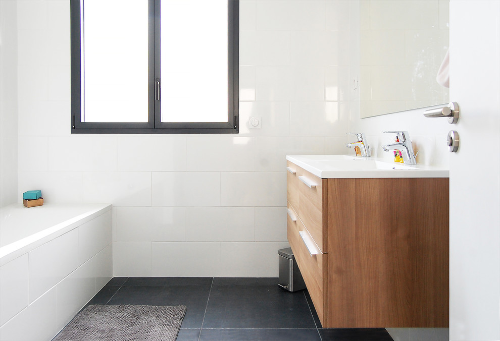 Esempio di una stanza da bagno padronale design di medie dimensioni con ante in legno chiaro, vasca sottopiano, doccia alcova, piastrelle bianche, lavabo sospeso, pavimento nero e porta doccia a battente