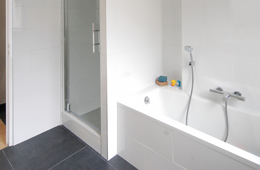 Immagine di una stanza da bagno padronale design di medie dimensioni con ante in legno chiaro, vasca sottopiano, doccia alcova, piastrelle bianche, lavabo sospeso, pavimento nero e porta doccia a battente