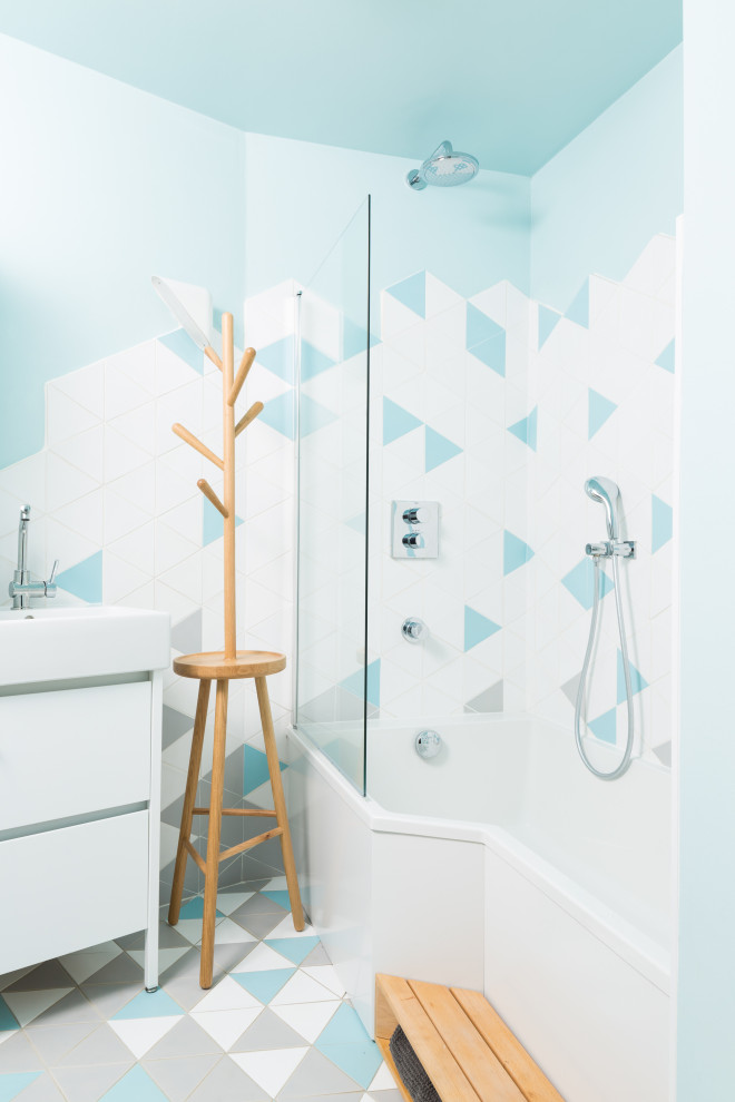 Inredning av ett modernt mellanstort vit vitt en-suite badrum, med svarta skåp, en dusch/badkar-kombination, flerfärgad kakel, cementkakel, betonggolv, ett konsol handfat, grått golv, ett hörnbadkar, en toalettstol med separat cisternkåpa, blå väggar, dusch med gångjärnsdörr och släta luckor