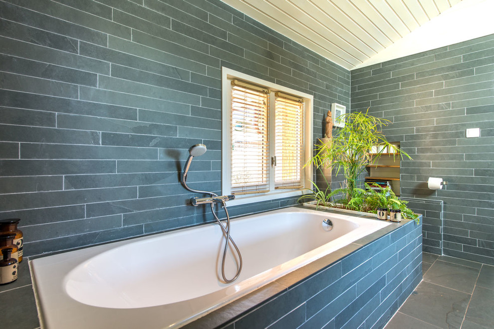 Inspiration pour une salle de bain principale nordique en bois clair de taille moyenne avec une baignoire encastrée, WC suspendus, un carrelage gris, du carrelage en ardoise, un mur gris, un sol en ardoise, un lavabo posé, un sol gris, une cabine de douche à porte coulissante et un plan de toilette gris.