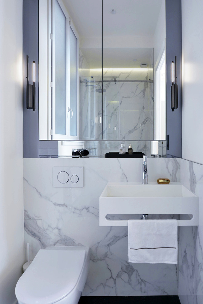Aménagement d'une petite salle d'eau moderne avec un placard à porte affleurante, WC suspendus, un carrelage blanc, du carrelage en marbre, un lavabo suspendu, un plan de toilette en marbre et un plan de toilette blanc.