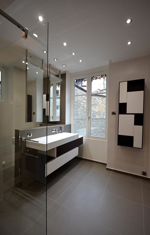 Idées déco pour une salle de bain principale contemporaine avec une douche à l'italienne, WC suspendus, un carrelage gris, mosaïque, un mur beige, un sol en carrelage de céramique, un plan vasque et un plan de toilette en surface solide.