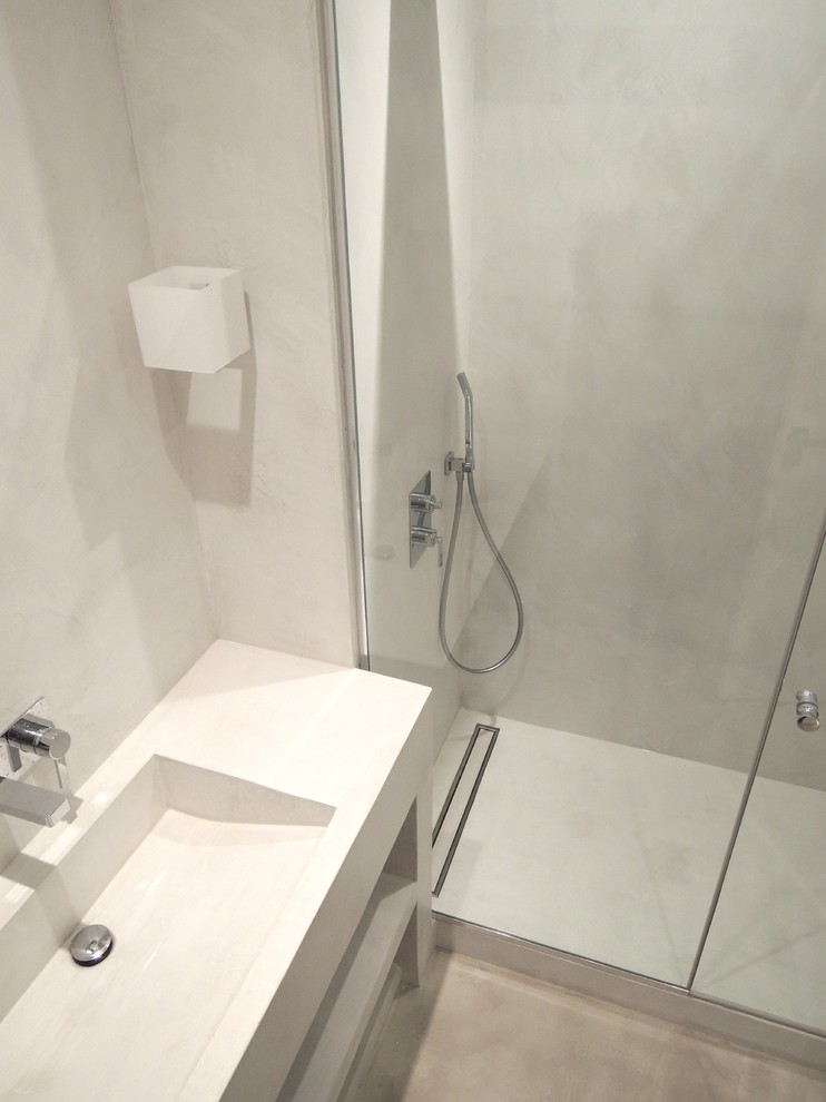 Bild på ett litet funkis badrum med dusch, med ett avlångt handfat, öppna hyllor, bänkskiva i betong, en kantlös dusch, vit kakel, vita väggar och betonggolv