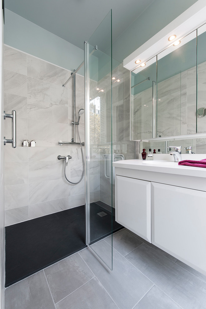 Réalisation d'une salle de bain principale design de taille moyenne avec une douche à l'italienne, un carrelage blanc, un carrelage bleu, un mur blanc, un sol gris, une cabine de douche à porte battante, un plan de toilette blanc et des portes de placard blanches.