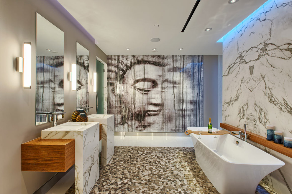 Foto på ett funkis brun en-suite badrum, med ett fristående badkar, svart och vit kakel, grå väggar, klinkergolv i småsten, ett integrerad handfat, träbänkskiva och grått golv
