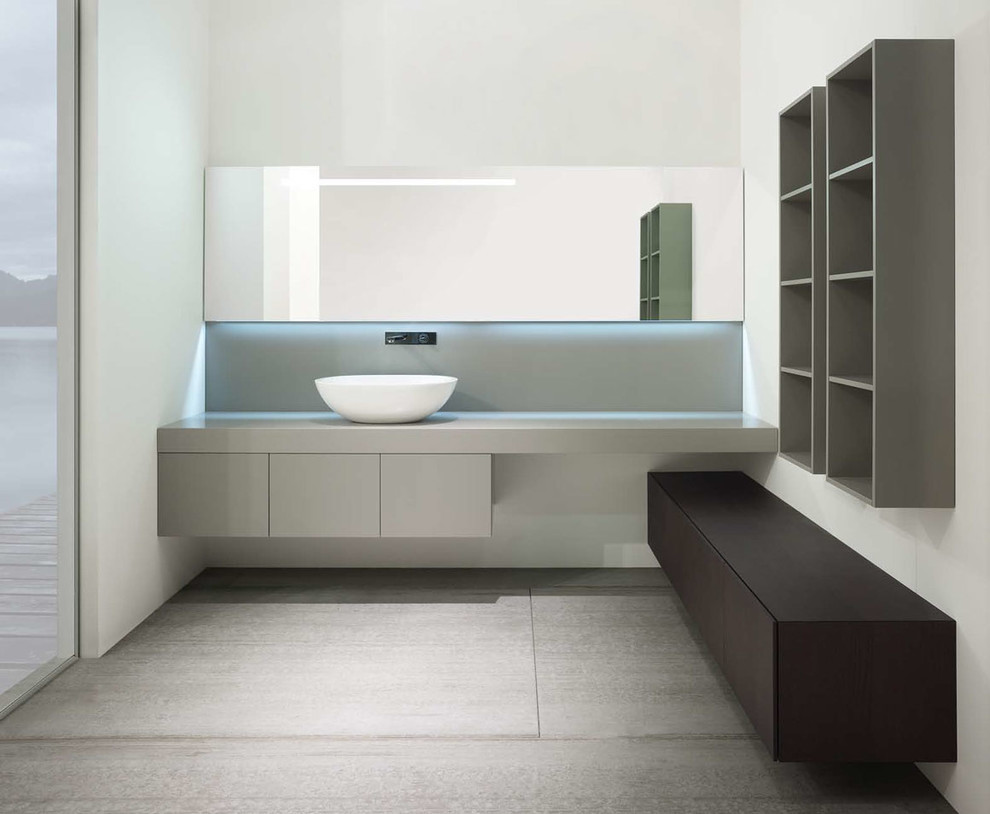 На фото: главная ванная комната в современном стиле с отдельно стоящей ванной, черно-белой плиткой, серыми стенами, полом из галечной плитки, монолитной раковиной, столешницей из дерева, серым полом и коричневой столешницей