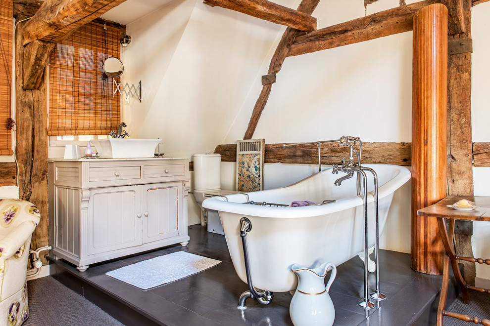 Exemple d'une salle de bain principale nature de taille moyenne avec des portes de placard beiges, une baignoire sur pieds, un mur blanc, une vasque, WC séparés et un placard avec porte à panneau encastré.