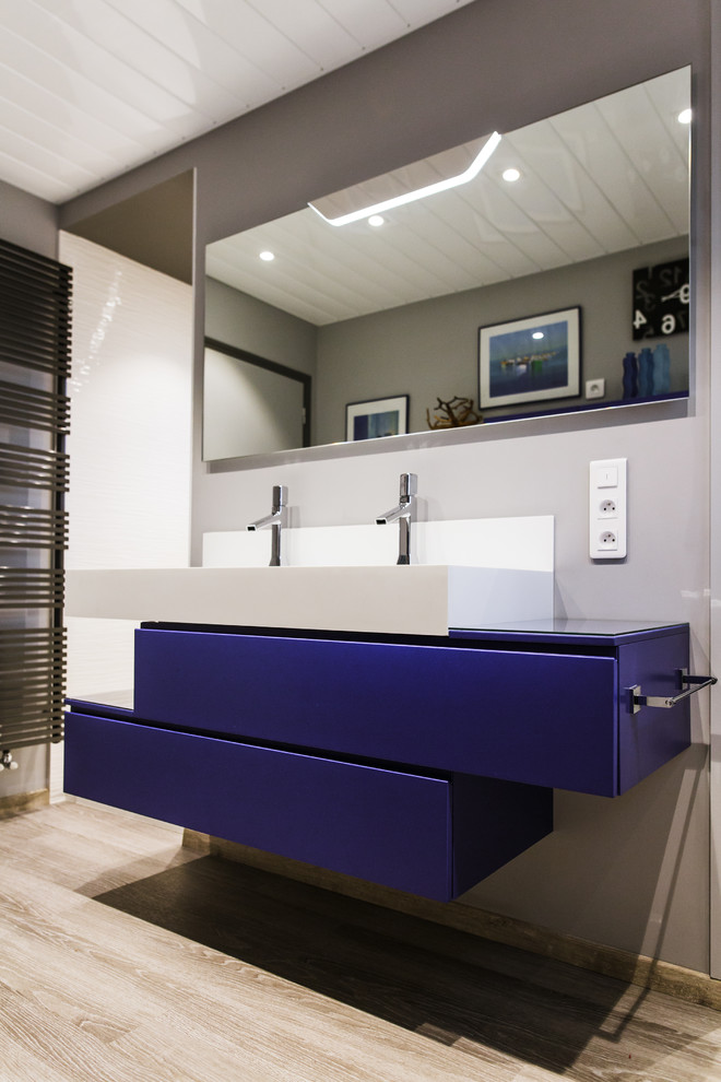 Idéer för ett mellanstort modernt en-suite badrum, med luckor med profilerade fronter, blå skåp, en kantlös dusch, en vägghängd toalettstol, vit kakel, keramikplattor, vita väggar, målat trägolv, ett konsol handfat, bänkskiva i akrylsten, grått golv och med dusch som är öppen
