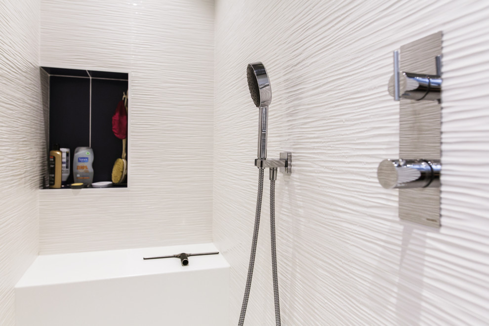 Bild på ett mellanstort funkis en-suite badrum, med luckor med profilerade fronter, blå skåp, en kantlös dusch, en vägghängd toalettstol, vit kakel, keramikplattor, vita väggar, målat trägolv, ett konsol handfat, bänkskiva i akrylsten, grått golv och med dusch som är öppen