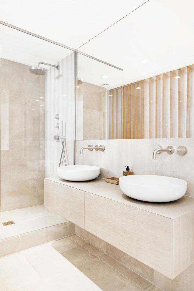 Idéer för att renovera ett mellanstort funkis en-suite badrum, med en kantlös dusch, en toalettstol med separat cisternkåpa, beige kakel, vit kakel, beige väggar, travertin golv, ett fristående handfat och kaklad bänkskiva