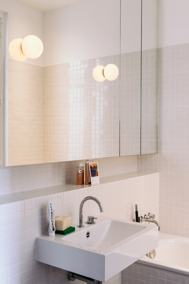 Cette image montre une grande salle de bain design avec un carrelage blanc, un lavabo suspendu, une baignoire en alcôve et mosaïque.