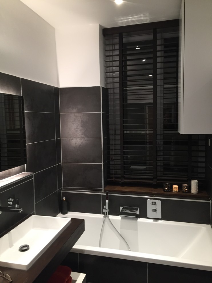 リヨンにある高級な小さなモダンスタイルのおしゃれなマスターバスルーム (アンダーマウント型浴槽、壁掛け式トイレ、黒いタイル、茶色い壁、アンダーカウンター洗面器、木製洗面台) の写真