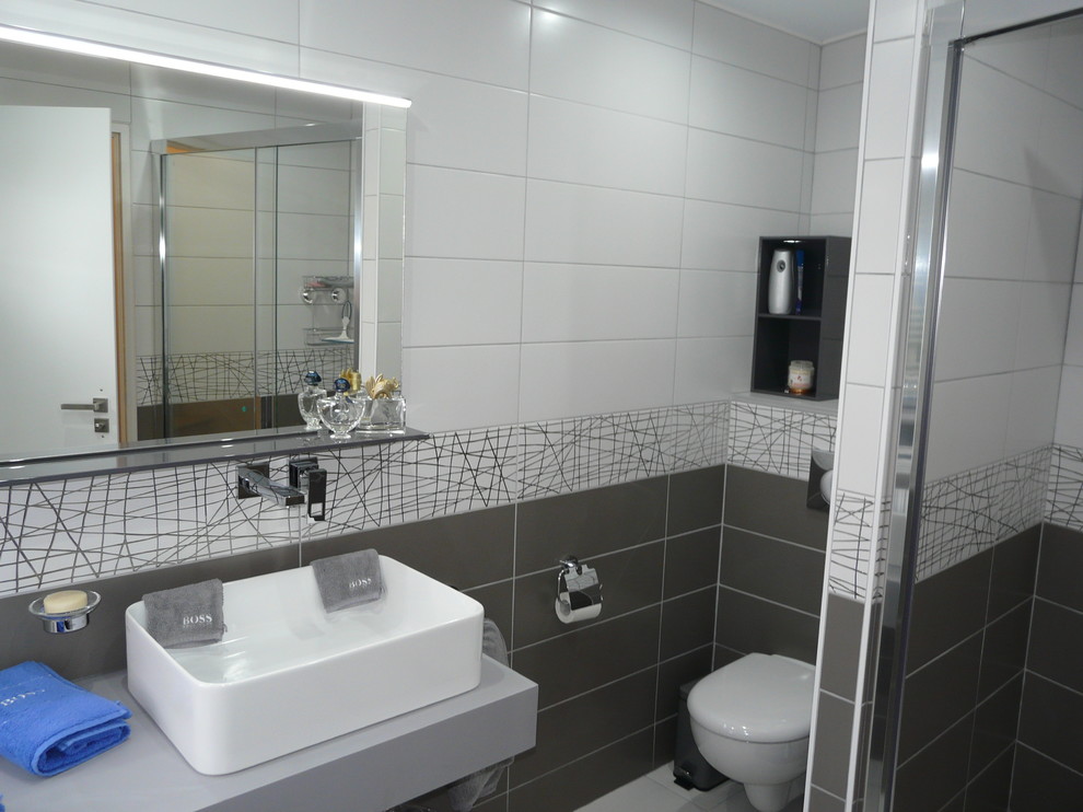 Inredning av ett modernt litet en-suite badrum, med en kantlös dusch, en vägghängd toalettstol, vit kakel, keramikplattor, grå väggar, klinkergolv i keramik, ett avlångt handfat och bänkskiva i kvartsit